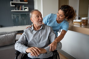 man sitting in a wheelchair with a younger female nurse next to him